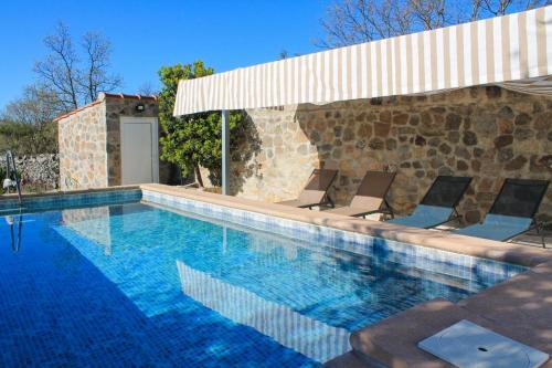 uma piscina com cadeiras e um guarda-sol em Quinta do Miradouro em Portalegre