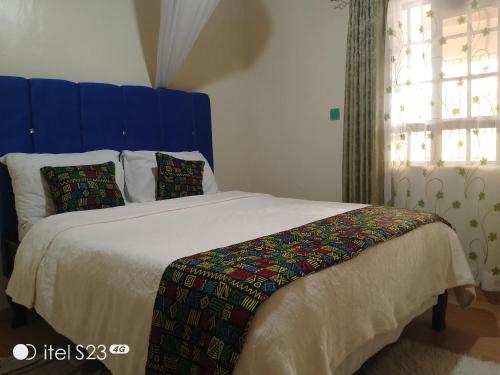 a bedroom with a large bed with a blue headboard at Maridadi place in Kakamega
