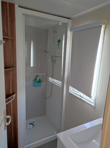 une salle de bain avec une douche avec une porte vitrée dans l'établissement CHEZ ISA - Mobil home 3 chambres, à Le Portel