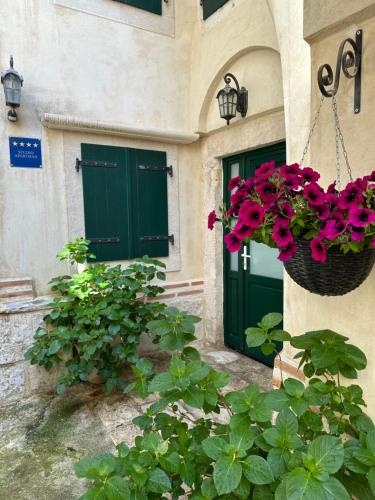 a house with green doors and flowers in a basket at Diocletian Wine studio apartment in Split