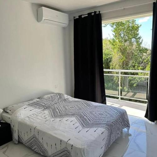 a bedroom with a bed and a large window at Au vert, proche des plages in Les Anses-dʼArlets