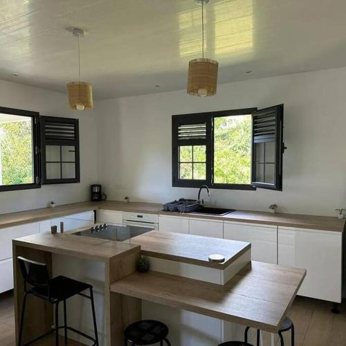 a kitchen with a table and some chairs and windows at Au vert, proche des plages in Les Anses-dʼArlets