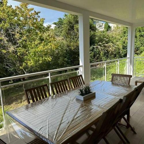 - une table en bois avec des chaises sur une terrasse couverte dans l'établissement Au vert, proche des plages, à Les Anses-d'Arlet
