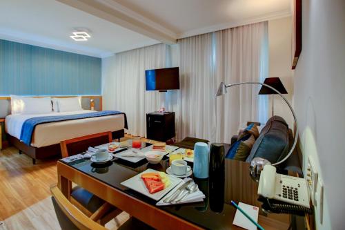 サンパウロにあるQuality Suítes Oscar Freireのベッドとデスクが備わるホテルルームです。