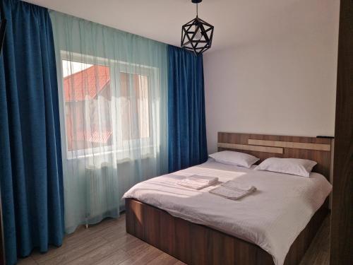 a bedroom with a bed with blue curtains and a window at Turquoise apartment in Petroşani