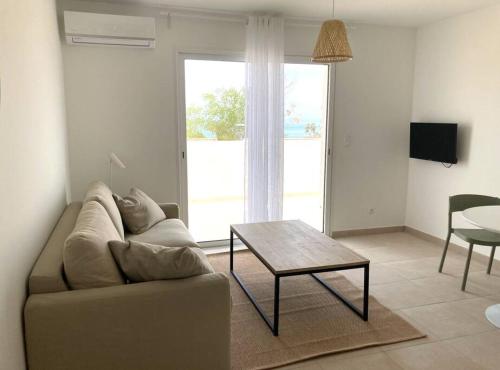 un salon avec un canapé et une table dans l'établissement Studio 2 personnes vue mer et pieds dans l'eau, à Linguizzetta