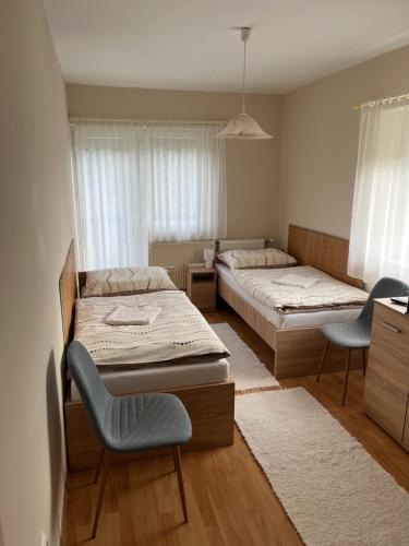 a bedroom with two beds and two chairs in it at Zsuzsi Vendégház in Zalaegerszeg