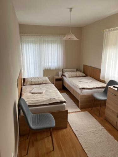 a bedroom with two beds and two chairs in it at Zsuzsi Vend&eacute;gh&aacute;z in Zalaegerszeg