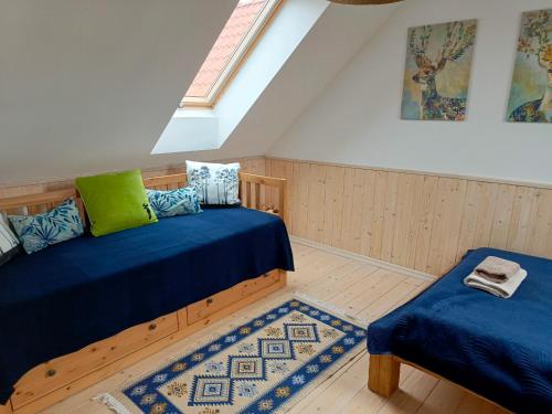 a attic room with two beds and a rug at Rozmaryn - Komfortowy domek całoroczny na Kaszubach in Borowy Młyn