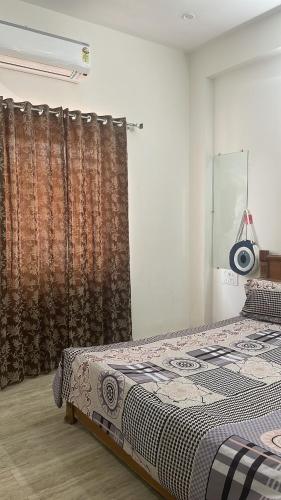 Schlafzimmer mit einem Bett und einem Fenster mit Vorhängen in der Unterkunft Sai udaipur home stay in Udaipur