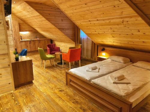 ein Schlafzimmer mit einem Bett und Stühlen im Dachgeschoss in der Unterkunft Hotel Porto Tara in Žabljak