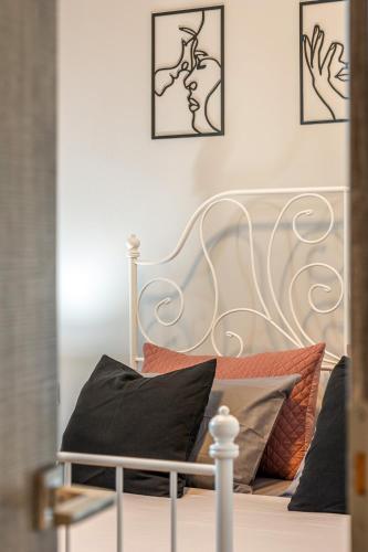a white bed with black pillows and pictures on the wall at Iliovasilema Luxury Apartment in Heraklio Town
