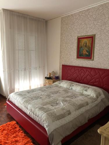 a bedroom with a large bed with a red headboard at La mimosa in San Mauro Pascoli