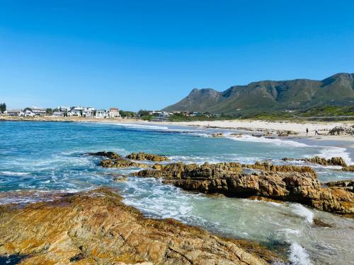 a beach with rocks and the ocean and mountains at Seapearl Oceanfront Villa and Cottage in Hermanus