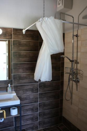 ein Bad mit einer Dusche und einem weißen Hochzeitskleid, das von einer Dusche hängt in der Unterkunft Zamárdi Trafóház in Zamárdi