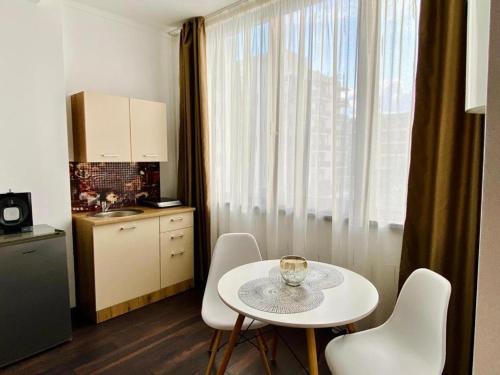 una cocina con una mesa y sillas blancas y una ventana en ApartHotel Near the Sea, en Mamaia Nord – Năvodari