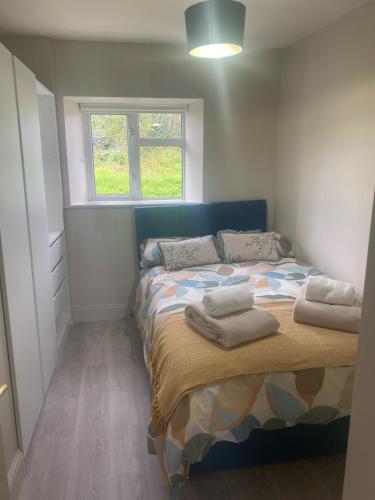 1 dormitorio con 1 cama con toallas en Cara's Cottage, en Kinawley