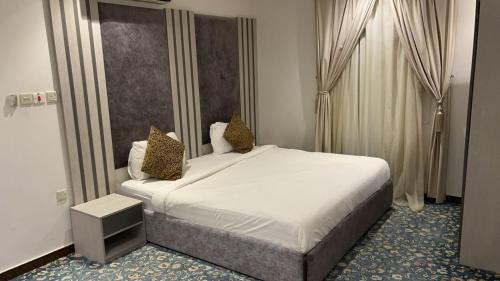 una camera da letto con un grande letto bianco con due cuscini di اجواء المساء للشقق المخدومة a Riyad