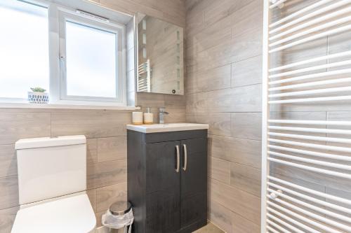 a bathroom with a toilet and a sink and a window at New 4BR family home sleeps 8 -10 people with free parking and contractors welcome in Birmingham