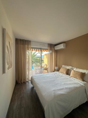 een slaapkamer met een groot wit bed en een balkon bij Appartement dans résidence avec piscine in Saint-Tropez