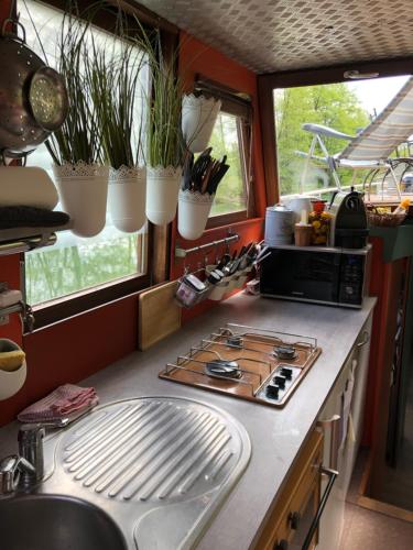 eine Küche mit einer Spüle, einem Herd und Fenstern in der Unterkunft Péniche hollandaise cosy in Dole