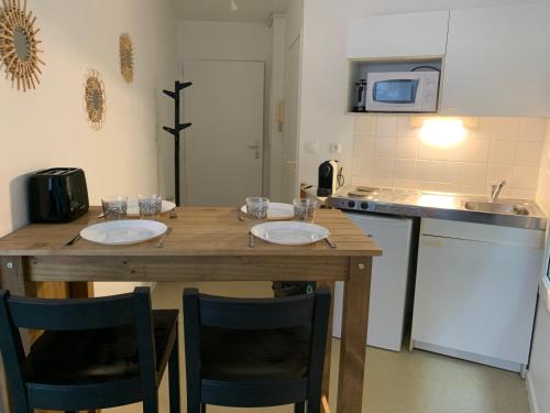 uma cozinha com uma mesa de madeira e 2 cadeiras em La colline aux oiseaux em Caen