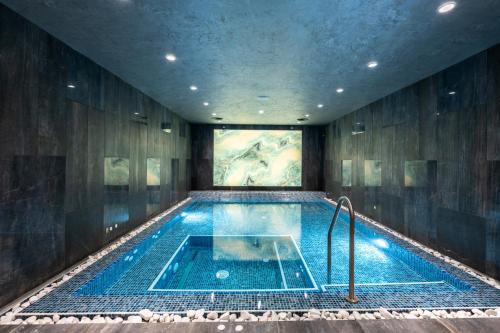 a swimming pool in a building with a painting on the wall at Empire Balneo & Spa Hotel in Hisarya