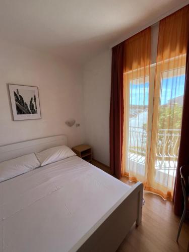 a bedroom with a white bed and a large window at Apartmani Šaldi in Pakoštane