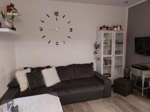 a living room with a couch and a clock on the wall at Apartament IKA in Gdańsk