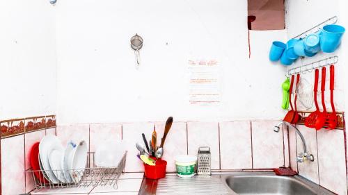 um balcão de cozinha com um lavatório com utensílios em Aguaymanto hostel em Pisac