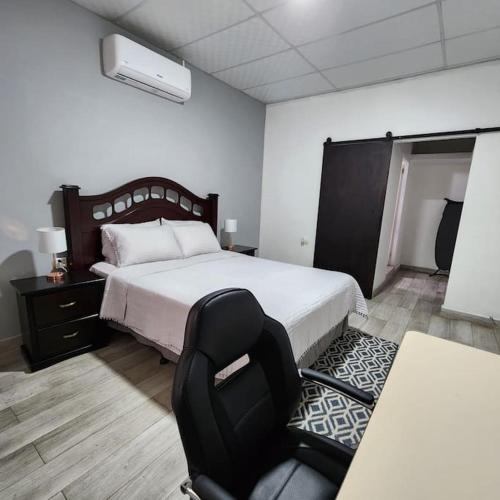 um quarto com uma cama, uma cadeira e uma secretária em Apartamento Alicia em Comayagua