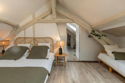 ein Schlafzimmer mit 2 Betten und einem Tisch mit einer Lampe in der Unterkunft Le Cottage de Chitenay in Chitenay