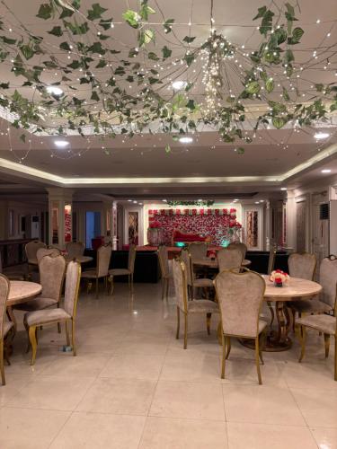 un comedor con mesas, sillas y luces en Hotel Golden Palace en Noida