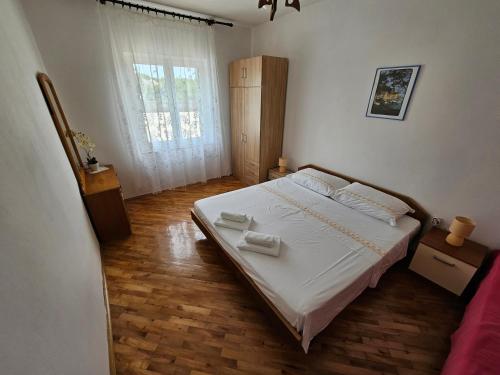 una camera da letto con un letto con lenzuola bianche e una finestra di Apartments Rusin a Krk