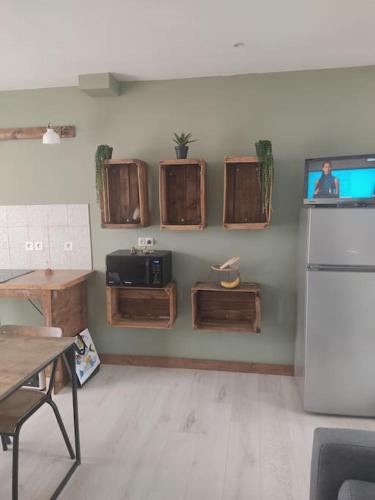 Il comprend une cuisine avec une table et une télévision murale. dans l'établissement Appt bord de mer /rez de jardin, à Notre-Dame-de-Monts