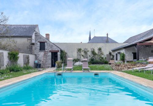 une piscine avec deux chaises et une maison dans l'établissement Le Cottage de Chitenay, à Chitenay