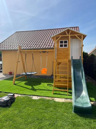 a playground with a slide and a play house at Betli Panzió in Zalaegerszeg