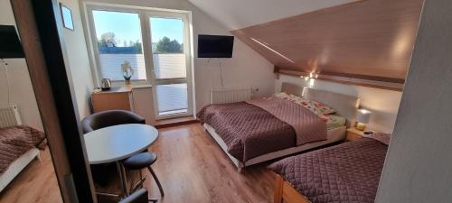a bedroom with two beds and a table and a window at Pogodna 3B in Mielno