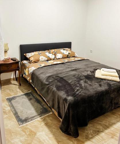 een slaapkamer met een bed met een zwarte deken en een tafel bij Apartman Nika in Požarevac