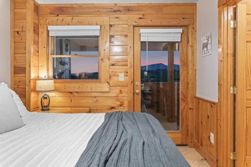 a bedroom with wooden walls and a bed and windows at Cozy Cabin in the Smokies!!! Fully Furnished and complete with community indoor and outdoor pools and spas, game and fitness rooms as well as a private Hot Tub in Pigeon Forge