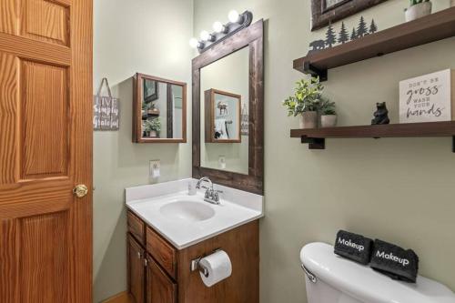 a bathroom with a sink and a toilet and a mirror at Cozy Cabin in the Smokies!!! Fully Furnished and complete with community indoor and outdoor pools and spas, game and fitness rooms as well as a private Hot Tub in Pigeon Forge