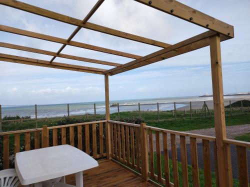 a deck with a bench and a view of the beach at Mobil home 2 chambres vue direct sur mer in Le Portel