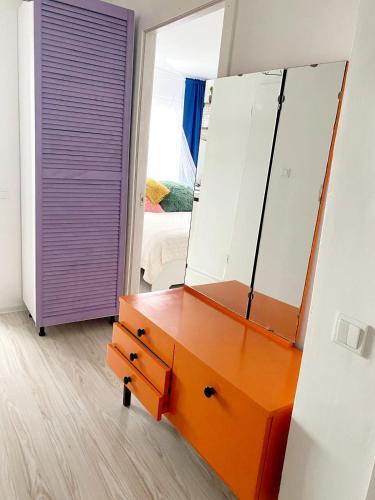 an orange dresser with a mirror and a purple door at Seaview Flat in Liepāja