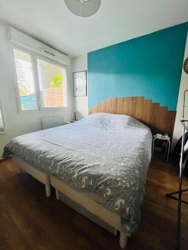 Schlafzimmer mit einem Bett mit blauer Wand in der Unterkunft Key Home Leman -T2 cosy-portes de Genève-jardin in Étrembières