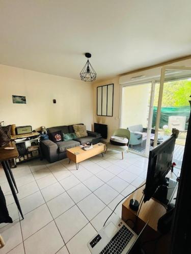 ein Wohnzimmer mit einem Sofa und einem Laptop auf dem Tisch in der Unterkunft Key Home Leman -T2 cosy-portes de Genève-jardin in Étrembières