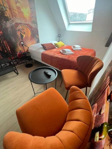 - une chambre dotée d'un lit avec des chaises orange et une table dans l'établissement Esprit Italie, joli studio au coeur de Mulhouse, à Mulhouse