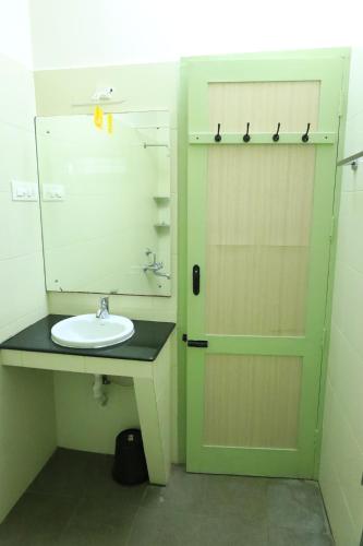 a bathroom with a sink and a door with a mirror at Transit Nest - Homestay Near Madurai Airport in Madurai