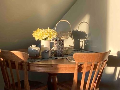 a table with a vase of yellow flowers on it at The Nest BnB 'mini suite' in Dorchester on thames