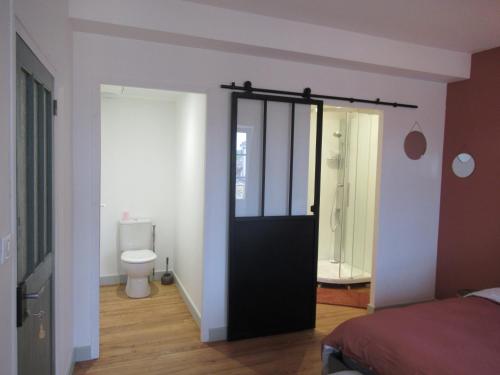 a bedroom with a door to a bathroom with a toilet at Appartement village in Simorre