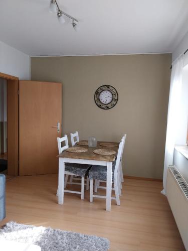 a dining room table with chairs and a clock on the wall at Beas Ferienglück in Busenberg